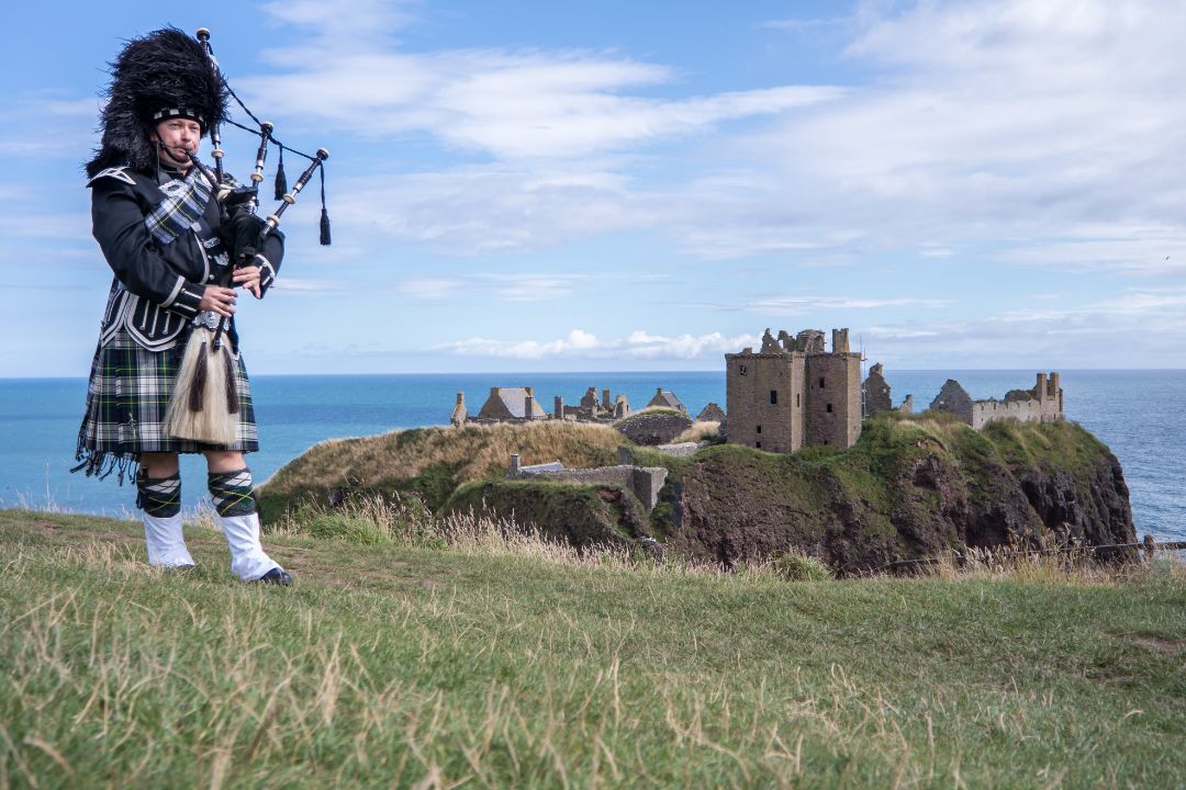 Bagpiper with Scottish castle in background